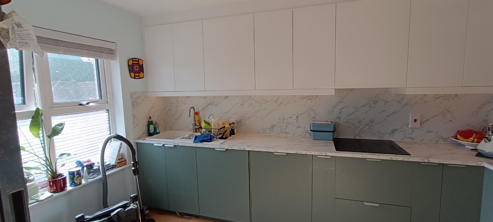 Modern sage green kitchen with white wall units and marble splashback